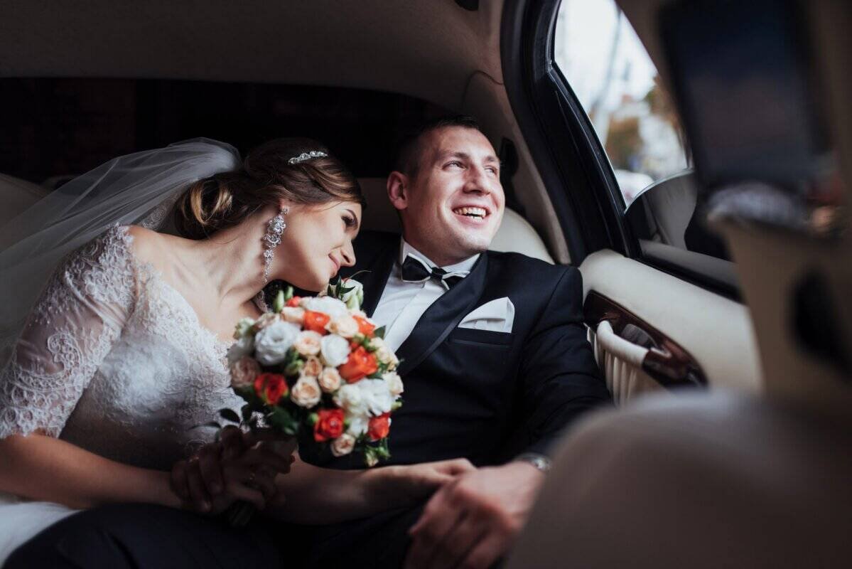 Wedding couple in a luxury car, celebrating their special day.