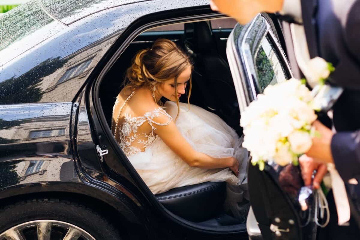 Bride exiting a black luxury car, ready for her wedding ceremony, showcasing premium chauffeur servi.