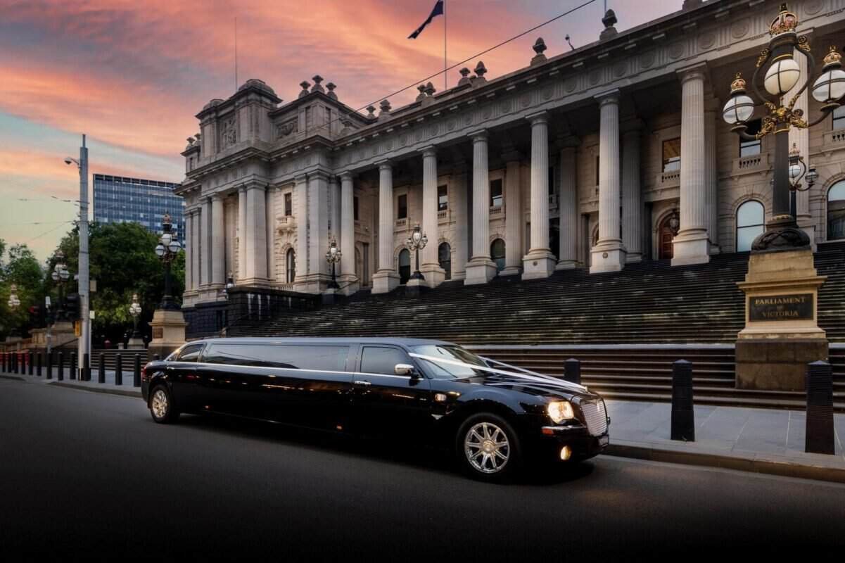 Luxury black limousine arriving at government building in Sydney at sunset.