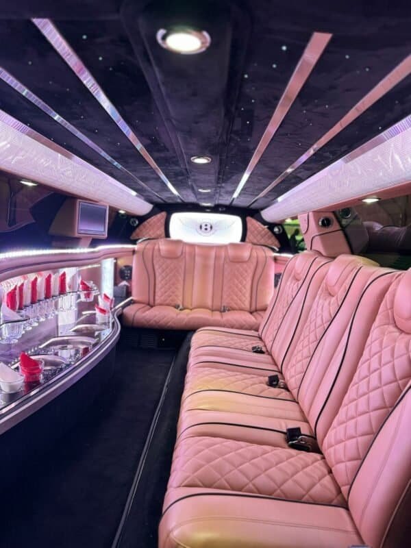 Luxury limousine interior with plush pink seats and ambient lighting.