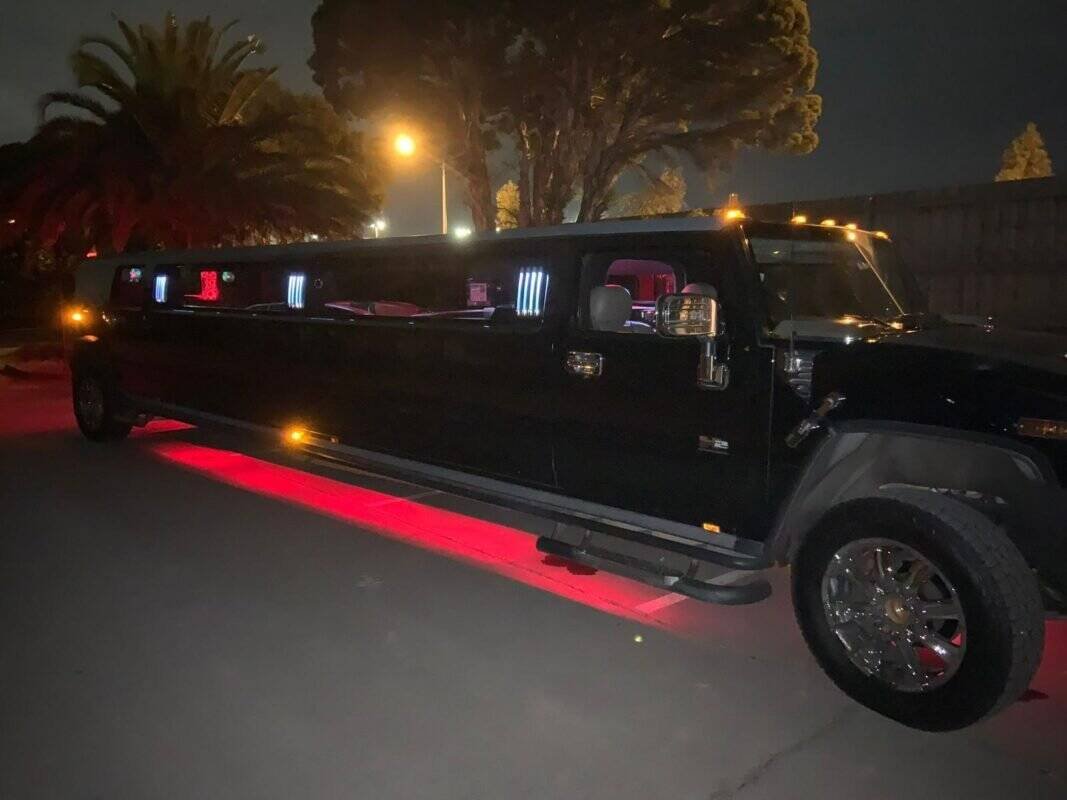 Luxury black limousine with underglow lighting at night.