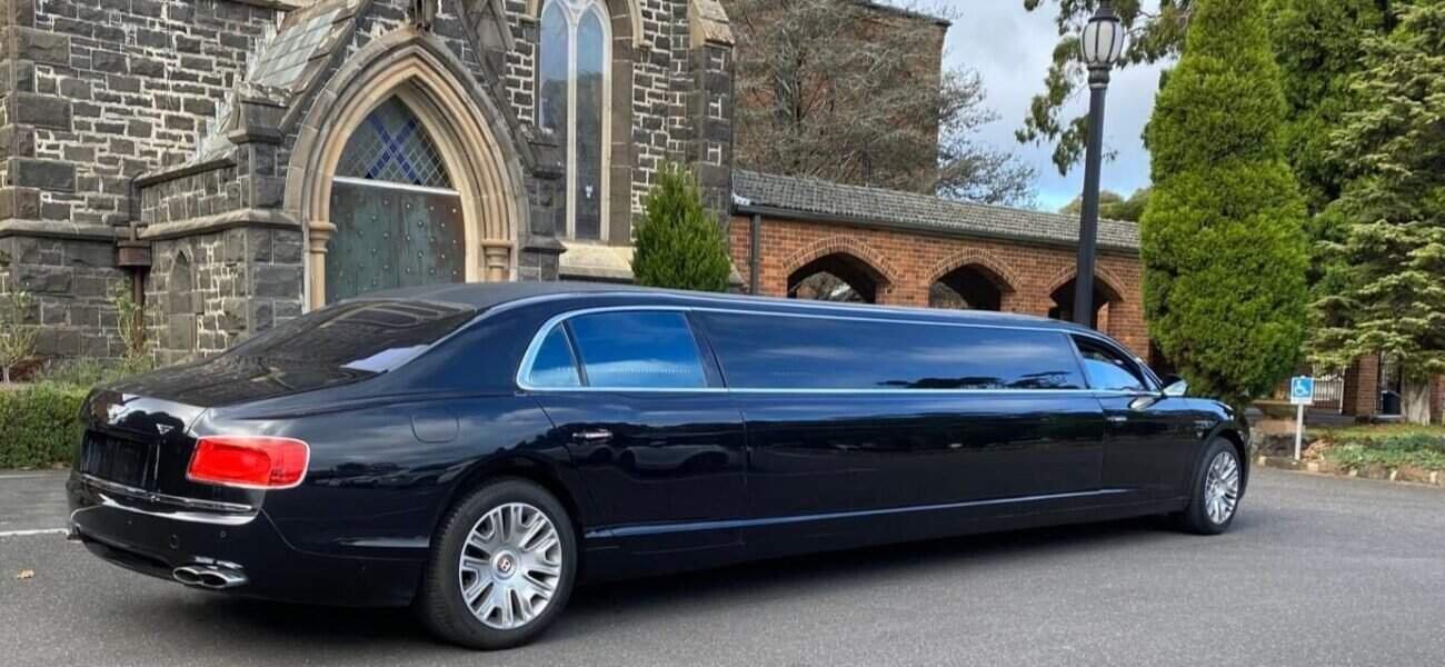 Luxury black limousine parked near historic church for events and transportation services.