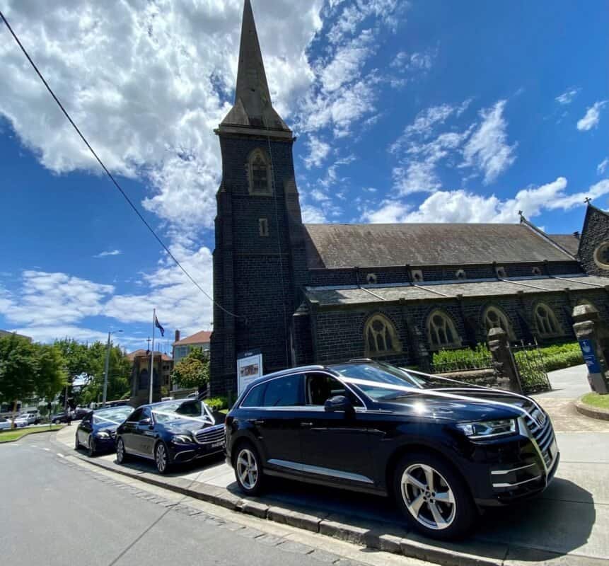 Premium cars parked outside historic church in Perth, Australia.