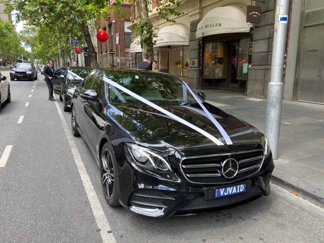 Mercedes-Benz luxury car parked on city street for chauffeur service.