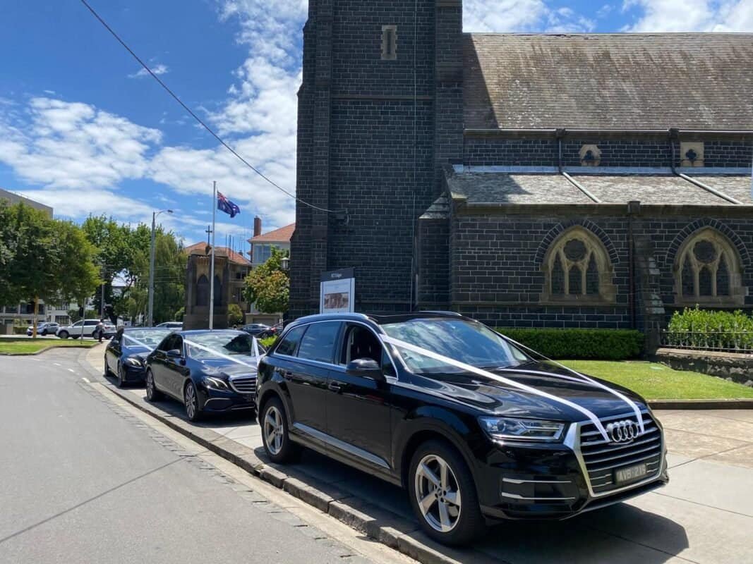 Luxury black Audi SUV parked outside historic church in Australia.